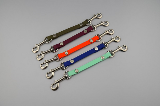 Set of colorful leather straps with metal hooks on a black background