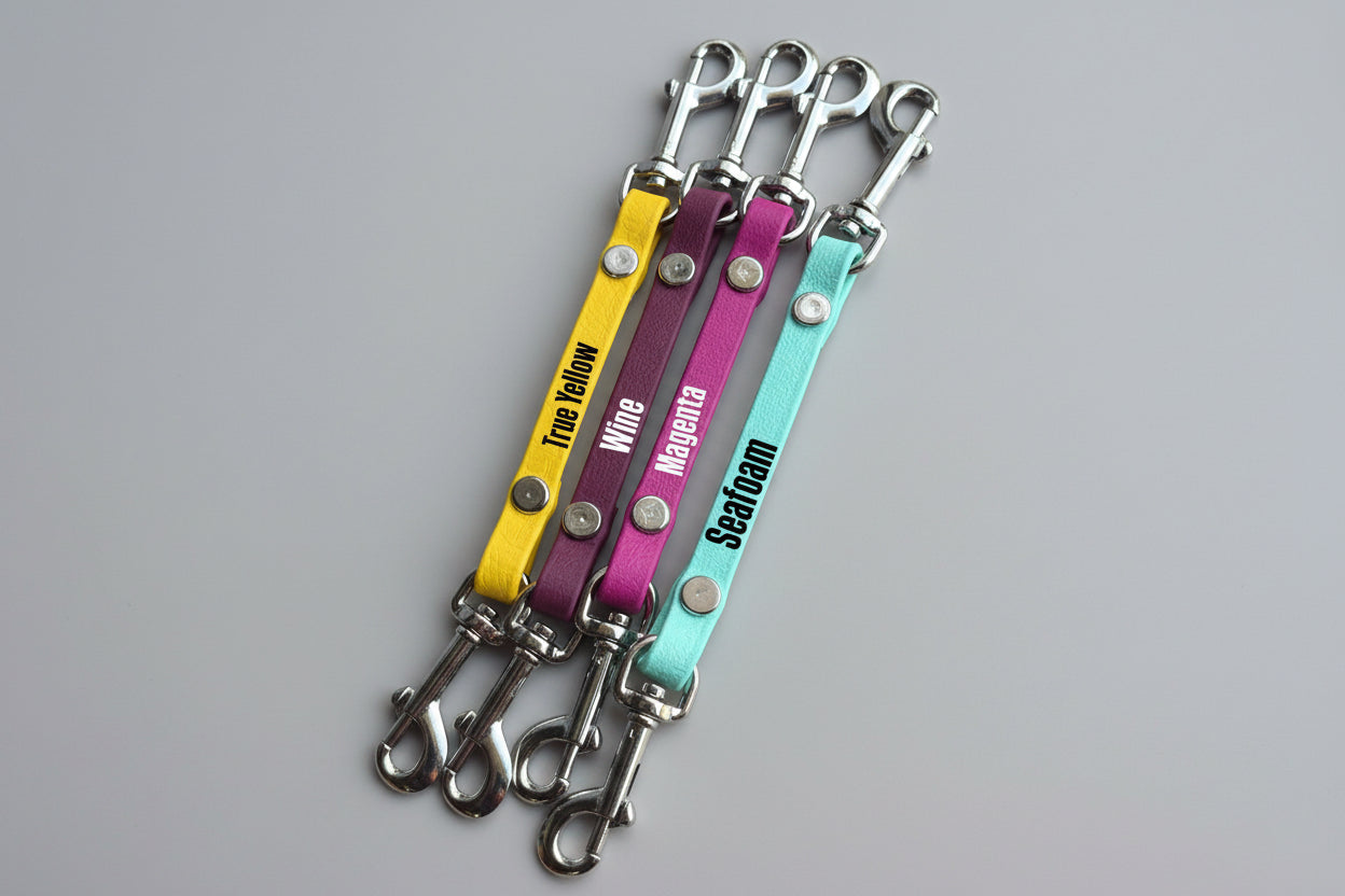 Four colorful keychains with metal hooks on a wooden surface, labeled 'True Yellow', 'Purple', 'Magenta', and 'Seagreen'.