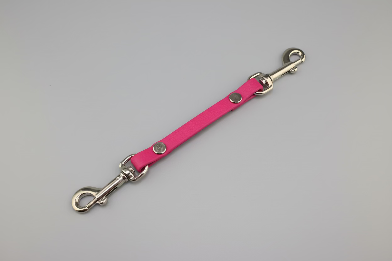 Pink leather dog leash with metal clips on a black background