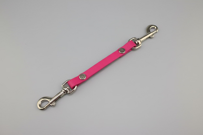 Pink leather dog leash with metal clips on a black background
