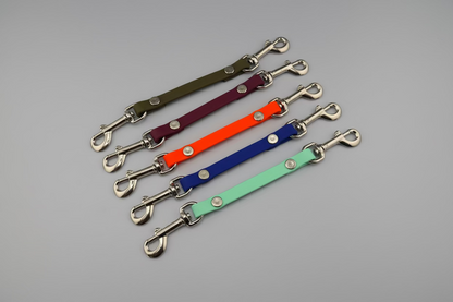 Set of colorful leather straps with metal hooks on a black background